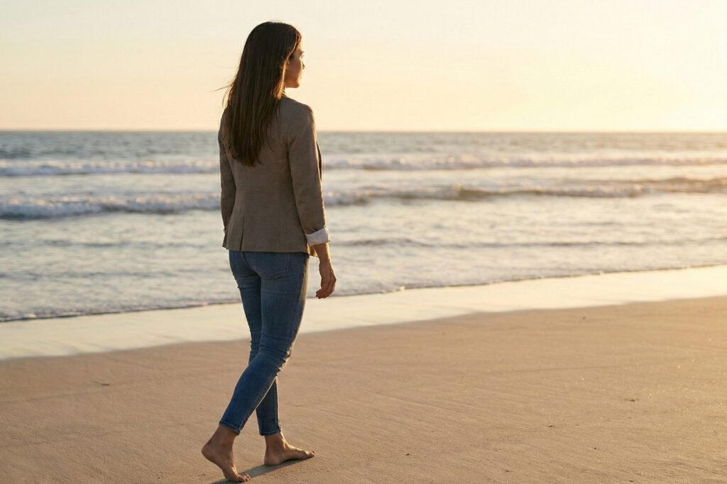 Mujer caminando sola con dignidad por la playa al atardecer, mirando al horizonte, simbolizando el retiro digno y la reconstrucción personal después de una ruptura.